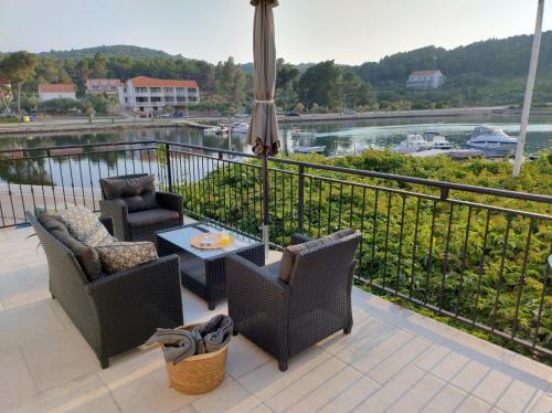 einen Balkon mit Stühlen, einem Tisch und einem Sonnenschirm in der Unterkunft Villa Nobilo in Lumbarda