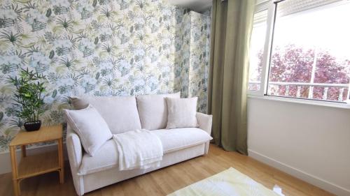 a living room with a white couch and a window at Apartamento Suite Los Deportes in Ponferrada