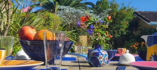 a table with a bowl of fruit and a vase of flowers at Bienvenue chez Lilaroma in Mérignac