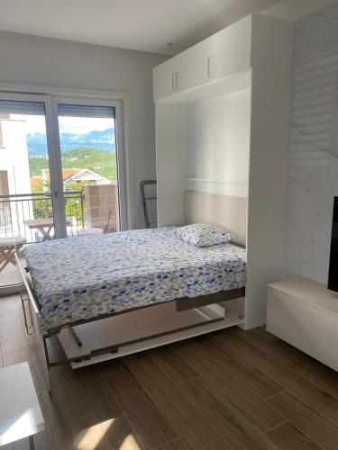 a bedroom with a bed in a room with a balcony at Lustica Bay Centrale Sparcle in Tivat