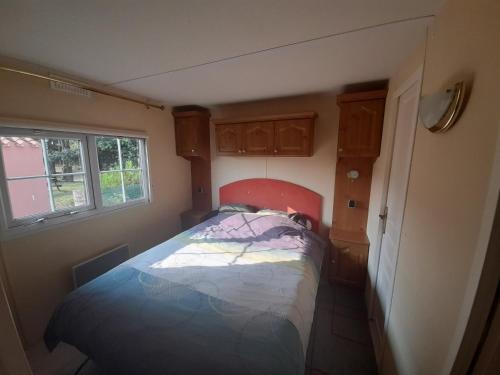 Mobil home climatisé في Bourgneuf-en-Retz: غرفة نوم صغيرة بها سرير ونافذة