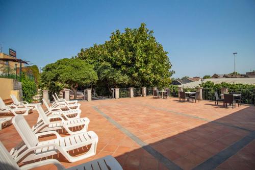 a group of white chairs and tables on a brick patio at Royal Playa Suite and Apartament -private parking- self chek out in Catania