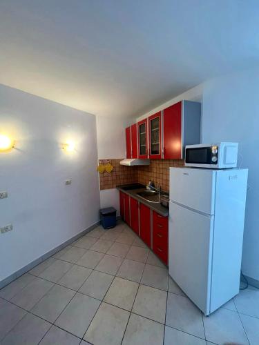 a kitchen with red cabinets and a white refrigerator at Villa Ružica in Dajla