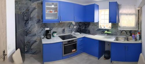 a blue kitchen with blue cabinets and a sink at Anchorage Apartment in Rachoni in Rachonio