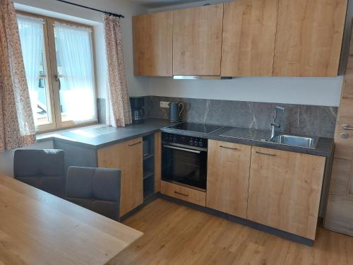 une cuisine avec des armoires en bois, un évier et une cuisinière dans l'établissement Haus Kurparkblick Ferienwohnung Lautersee, à Mittenwald