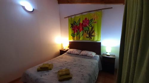 a bedroom with a bed with two lamps and a painting on the wall at Cabañas Isla de Pascua in Hanga Roa