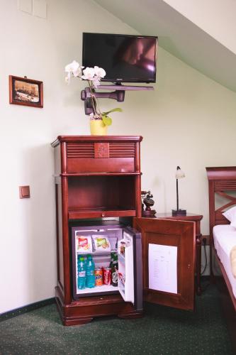 a room with a refrigerator with a tv on a wall at Pension Brasovu Vechi in Braşov