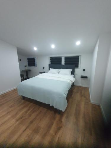 a bedroom with a large white bed and wooden floors at MB Apartman in Čapljina