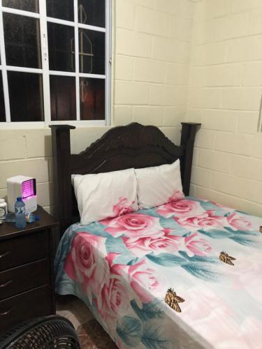 um quarto com uma cama com rosas cor-de-rosa em The Short STOP free Breakfast private Apartment em Monte Plata