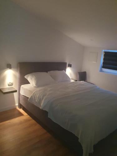 1 dormitorio con 1 cama grande con sábanas blancas y ventana en MB Apartman, en Čapljina