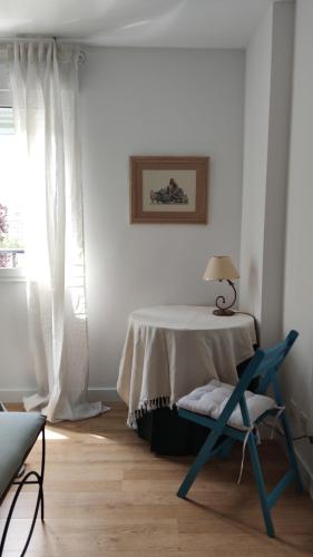 a white room with a table and a blue chair at Apartamento Suite Los Deportes in Ponferrada