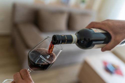 a person pouring wine into a wine glass at Belvárosi Nemes Apartmanház Szekszárd in Szekszárd