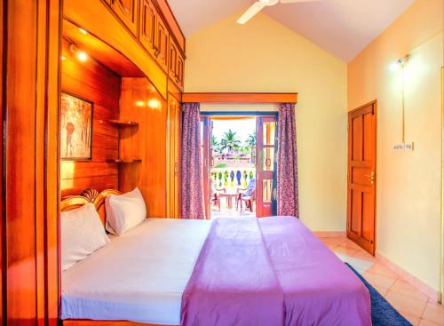 ein Schlafzimmer mit einem großen Bett und einem Balkon in der Unterkunft 'Golden Sea Breeze' Beach villa in Benaulim