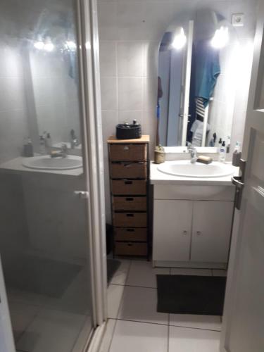 uma casa de banho com dois lavatórios e dois espelhos em Appartement proche étang de thau em Sète