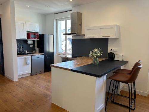 a kitchen with white cabinets and a black counter top at Appartement confortable de 80m2 Centre ville de Quimper & Parking privé in Quimper