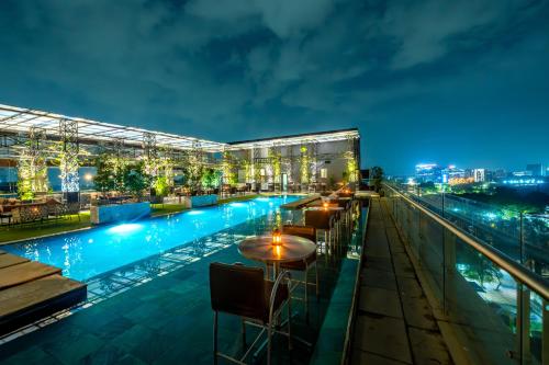 a hotel rooftop with a pool at night at O Hotel Pune in Pune