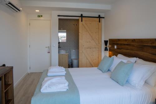 a bedroom with a large bed with white sheets and blue pillows at Casa Dona Maria in Montargil
