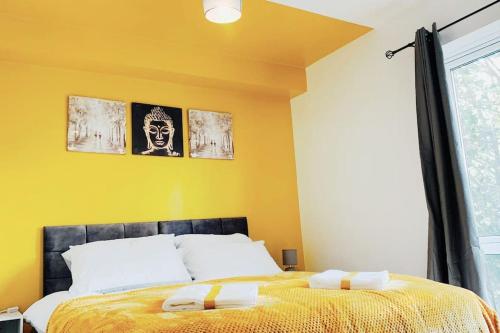 een slaapkamer met een bed en een gele muur bij 2 Bed Apartment with Free Parking in Chelmsford