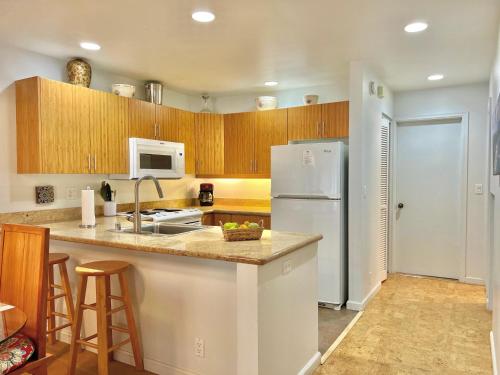 a kitchen with a white refrigerator and wooden cabinets at Maui Kamaole D208 in Wailea