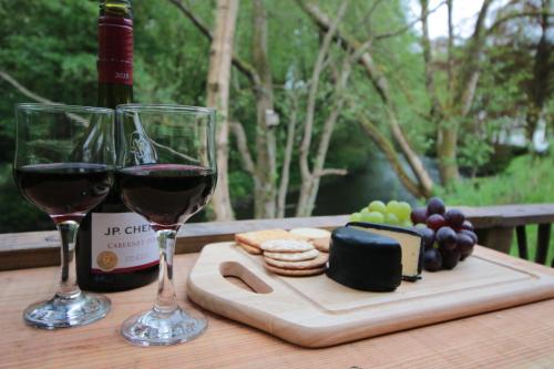 two glasses of wine and a cutting board with cheese and grapes at Caban Delor. Off-grid glamping experience. Walking distance into Caernarfon. 20-min drive to Snowdonia or Anglesey. in Caernarfon