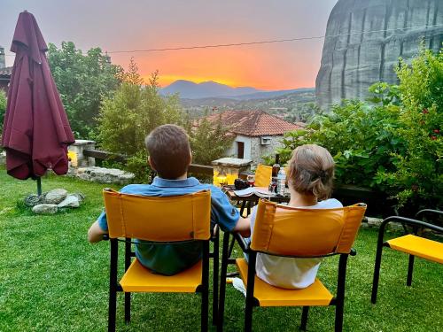 d'un homme et d'une femme assis sur des chaises pour observer le coucher du soleil dans l'établissement Archontiko Mesohori Meteora, à Kalambaka