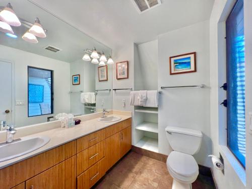 a bathroom with two sinks and a toilet and a mirror at Maui Kamaole D208 in Wailea