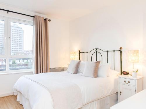 a white bedroom with a large bed and a window at Oakdale Apartments in Woking