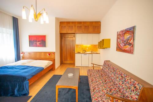 a bedroom with a bed and a couch and a kitchen at Villa Gabriela in Pörtschach am Wörthersee