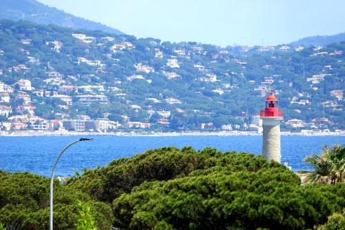 un phare rouge et blanc sur une colline à côté de l'eau dans l'établissement Family nest overlooking the Gulf of Saint-Tropez, à Saint-Tropez