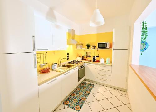eine Küche mit weißen Schränken und gelben Wänden in der Unterkunft Re del MARE - [Lounge con vista da SOGNO] in Porto Recanati