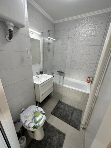 een badkamer met een toilet, een wastafel en een bad bij Sóstó Forest Apartman in Nyíregyháza