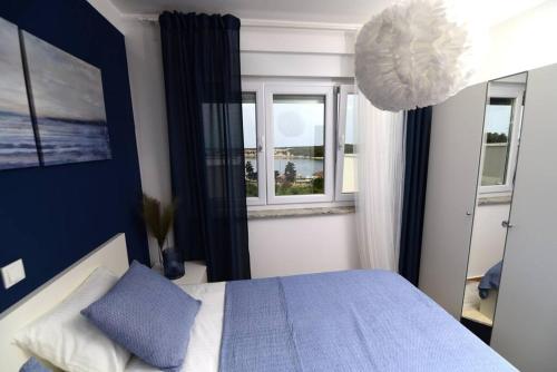 a bedroom with a blue and white bed and a window at Apartman Eva in Šimuni