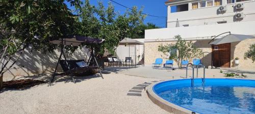 ein Pool mit Sonnenschirm und ein Gebäude in der Unterkunft Apartments Villa Mihaela in Banj