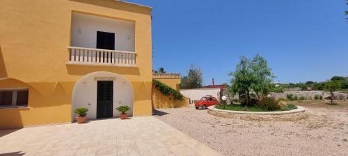 a yellow building with a balcony and a car in a driveway at Villa PARADISO - Tra Ulivi e Tramonti da Cartolina in Muro Leccese