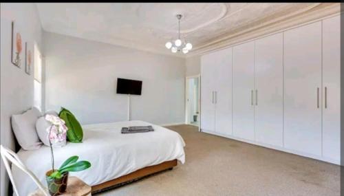 a white bedroom with a bed and white cabinets at East Prestige lodge in Johannesburg