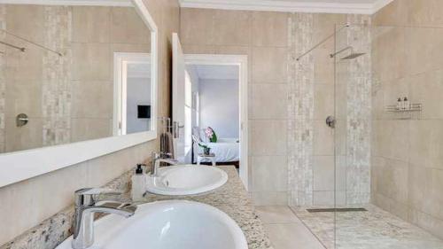 a bathroom with two sinks and a mirror and a shower at East Prestige lodge in Johannesburg