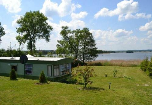 ein grünes Haus auf einem Feld neben einem See in der Unterkunft Domek Holenderski in Mikołajki