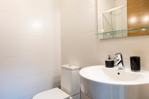 uma casa de banho branca com um lavatório e um WC em Loft 2 by Basquelidays em Hondarribia