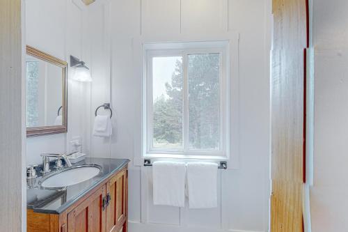 een witte badkamer met een wastafel en een raam bij Boat House in Shelter Cove