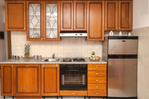 cocina con armarios de madera y nevera de acero inoxidable en Apartment Nia en Rabac