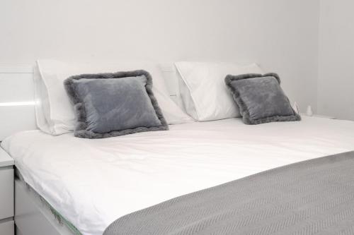 a white bed with two gray pillows on it at Apartment Nia in Rabac