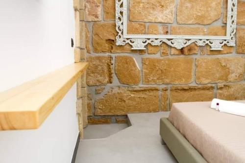 um quarto com uma parede de tijolos, uma cama e um espelho. em ARENARIA B&B em Avola