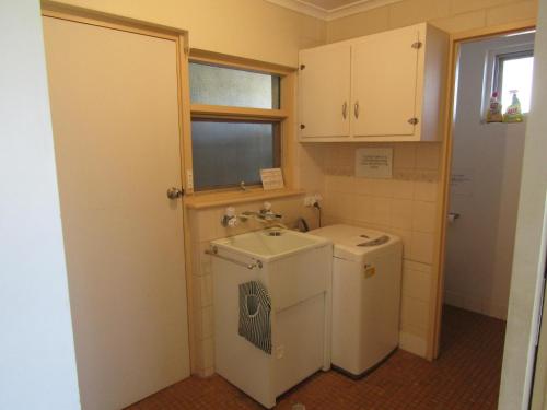 a small bathroom with a sink and a washing machine at Little Ray of Sunshines by the Sea in Edithburgh