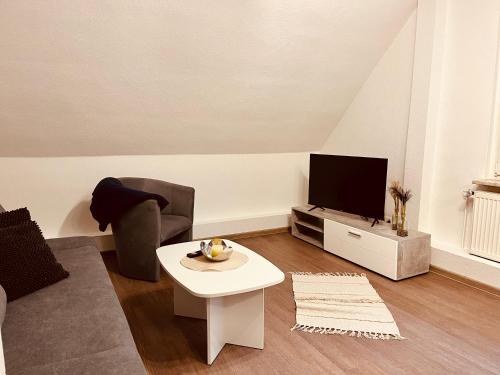 - un salon avec un canapé, une télévision et une table dans l'établissement Apartment-am-Burgberg, Harztor, à Harztor