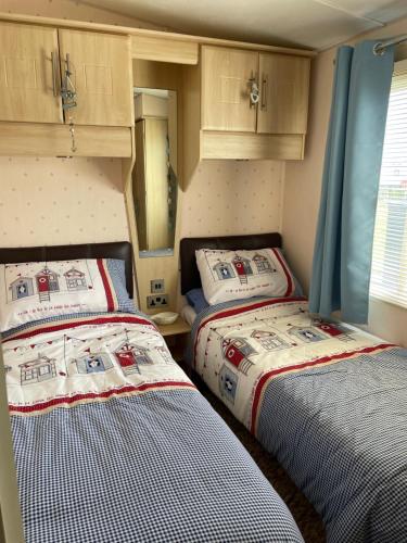 two beds in a small room with blue curtains at Konies Place Golden Anchor in Chapel Saint Leonards