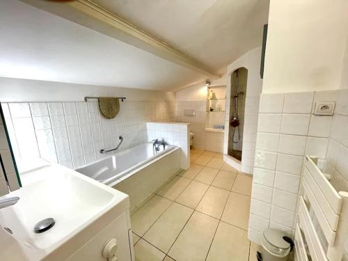 une salle de bain blanche avec une baignoire et un lavabo dans l'établissement Maison de vacances vue mer, à La Garonnette-Plage
