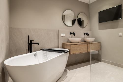 a white bath tub in a bathroom with two sinks at BizStay Harbour I Scheveningen Apartments in Scheveningen