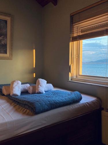 uma cama com um cobertor azul e uma janela em Luxury Beach Villa em Skála