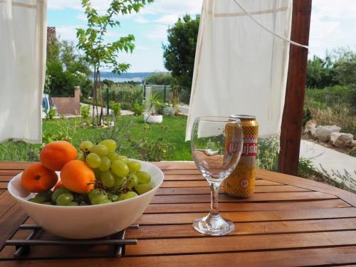 a bowl of fruit and a glass of wine on a table at Kuća za odmor Lara in Kaštela
