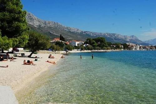 a group of people laying in the water on a beach at Kuća za odmor Lara in Kaštela